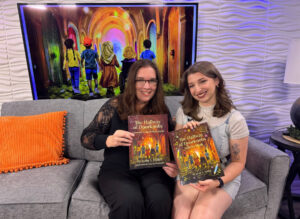 Lynn A. Haller, LCSW, author of The Hallway of Doorknobs, seated on a studio couch holding her children's book alongside a Studio 814 host holding The Hallway of Doorknobs Activity Book. The book's cover illustration is displayed on a large screen behind them during a segment on WTAJ's Studio 814.